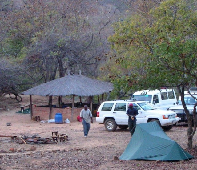The thatched 'kitchen replacement', the bench at the back where the little boys sat, the blue water barrel and last night's fire (that's Victor's tent not ours btw)